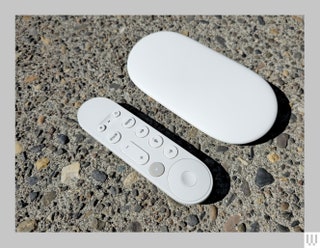 Small white remote with a few buttons beside a flat white elongated discshaped device