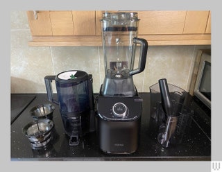 Blender with black base and additional accessories such as another container sitting on a black kitchen counter