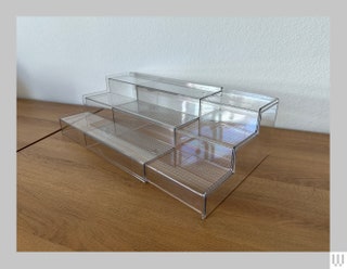 Side view of the Container Store clear 3tier staircase shaped spice rack organizer on wooden surface