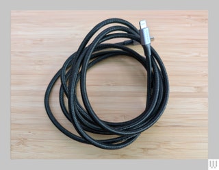 Black UGreen USBC to Lightning Cable wrapped in a circle sitting on wooden surface