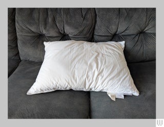 Front view of Fluff Co Down Pillow a white pillow on a grey couch