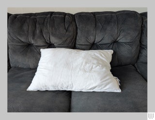 Front view of Fluff Co Down Alternative Pillow a white pillow on a grey couch