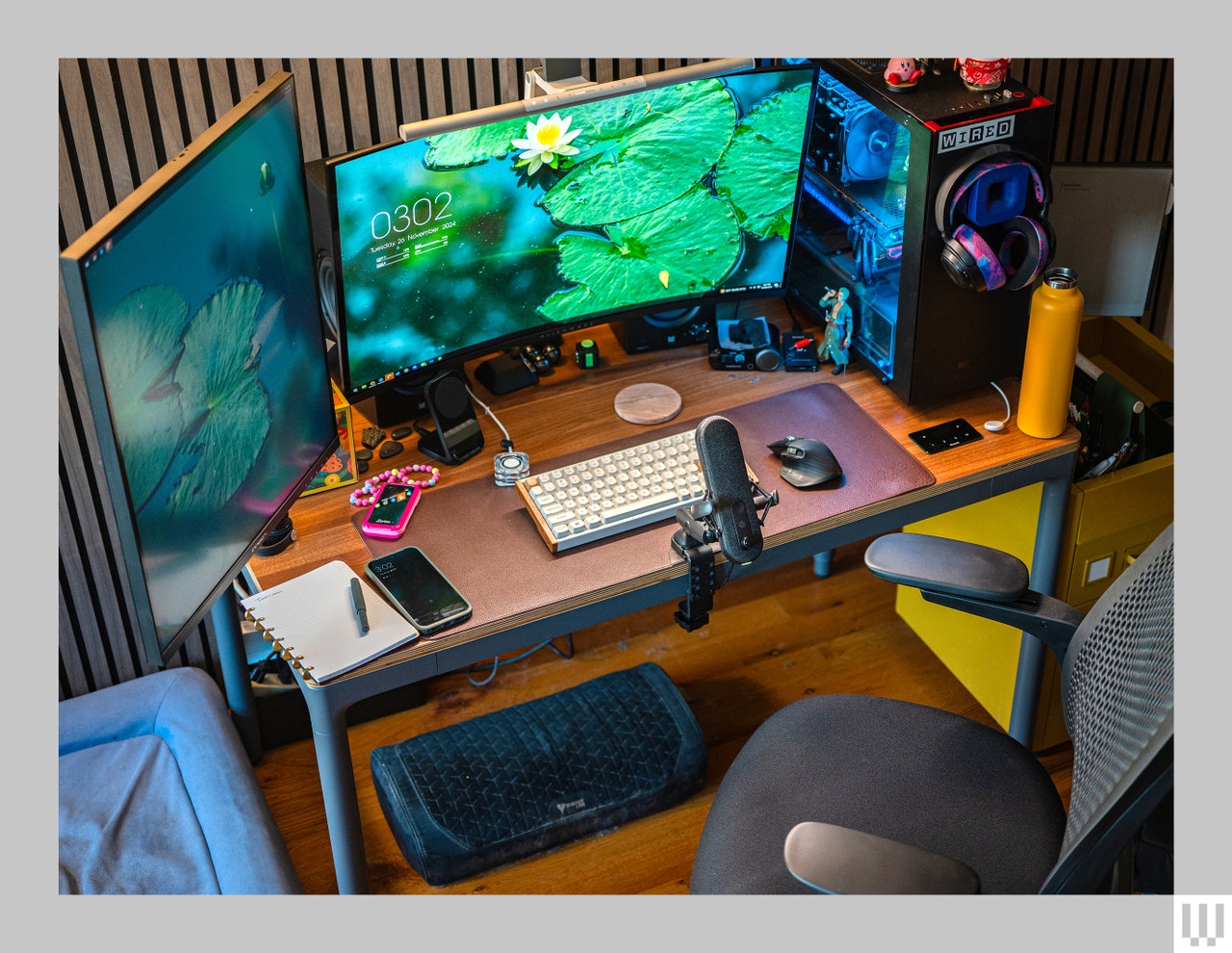 Front view of Branch Four Leg Standing Desk with computer monitors, keyboard, microphone and other work items on top