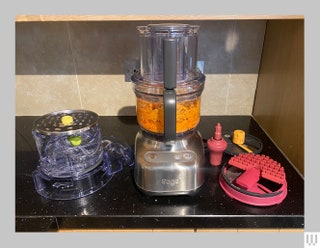 Breville Paradice 9 a silverbased blender with orange food inside and additional accessories on either side