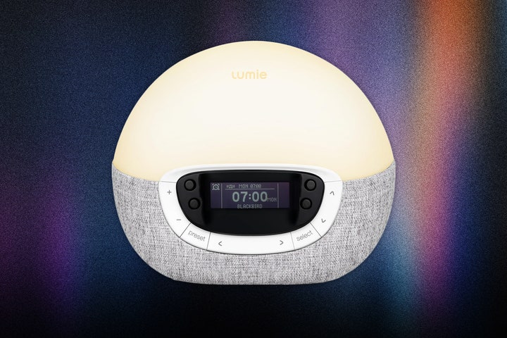 Lumie Shine 300 a sphereshaped alarm clock with an illuminated white top and fabric bottom that includes buttons...