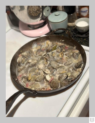 Smithey Forge Deep Farmhouse Skillet on a white stove with clams and broth inside