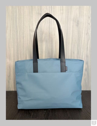 Away The Everywhere Tote in blue with thin black handles and an exterior pocket