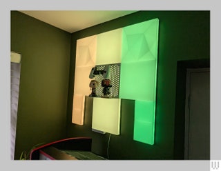 Nanoleaf Blocks illuminated panels installed on an interior room wall glowing with yellow and green light