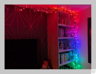 Twinkly Cluster a string of rainbow colored lights strung along the top and side of a tall bookcase running along the...