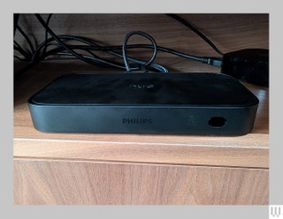 Front view of the Philips Hue Play HDMI Sync Box a rounded rectangular device with cords coming from the back