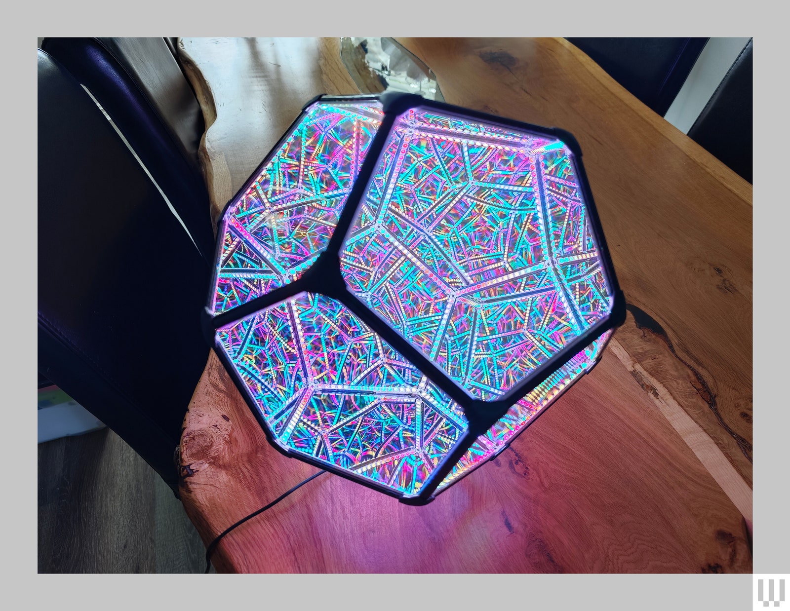 Exoy One a hexagonal 3D shaped smart light with black trim along the edges illuminating pink and blue light