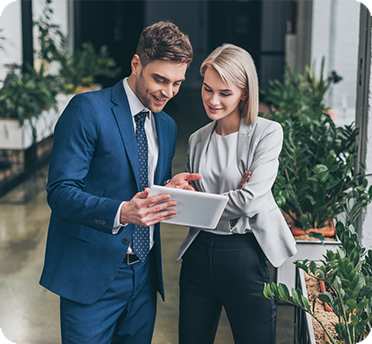 Two people standing looking at a tablet computer inside an office