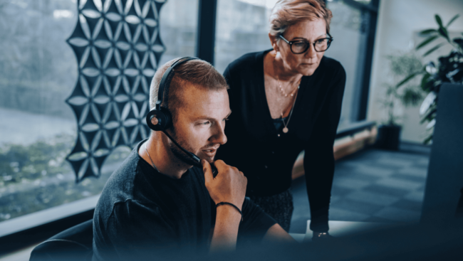 A person wearing a headset and a person looking at something