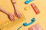 Hands typing on a keyboard surrounded by telephones