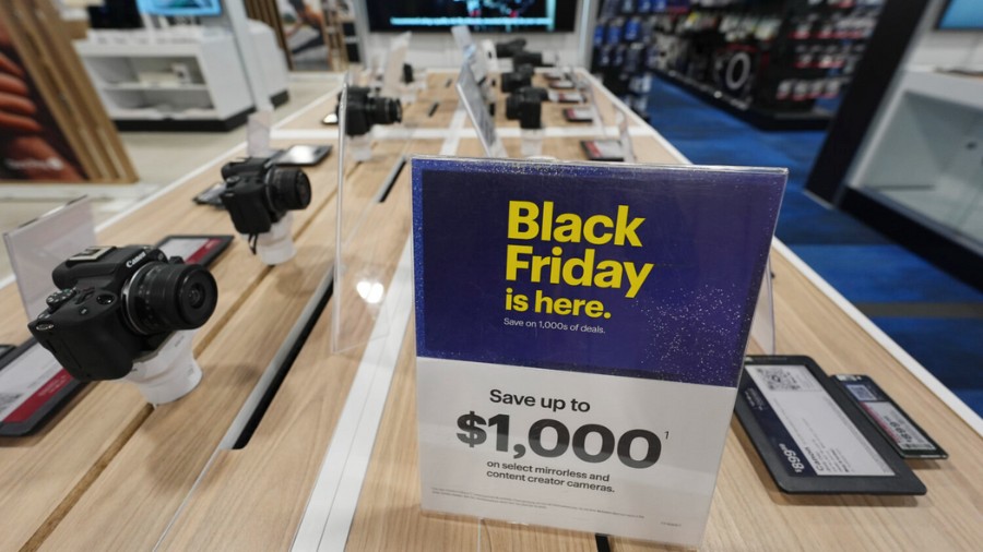 Image: A sign promoting Black Friday deals sits on table with a display of mirrorless cameras in a ...