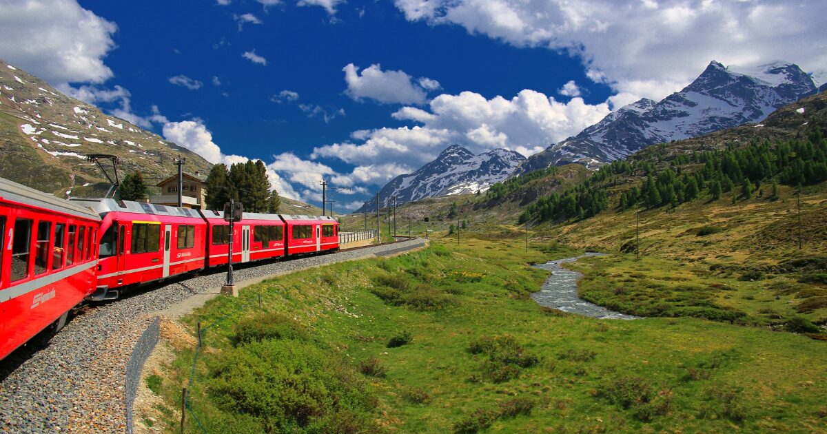 スイスの片田舎を赤い列車が走る風景