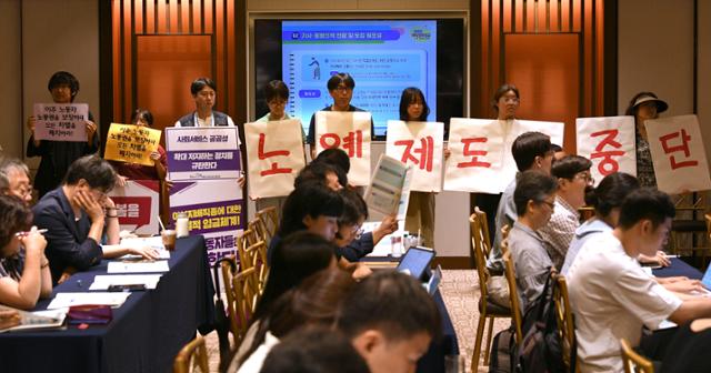 지난해 7월 31일 서울 중구 로얄호텔에서 고용노동부 주최로 열린 '외국인 가사근로자 도입 시범사업 관련 공청회'에서 한국여성노동자회 등 시민사회단체 회원들이 '노예제 도입중단'이 적힌 피켓을 들고 있다. 한국일보 자료 사진