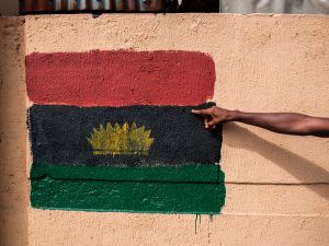 A man points at a Biafran flag painted on a wall on Old Market road in Onitsha on May 30, 2017, during a shutdown in commemoration of the 50th anniversary of the Nigerian civil war. Nigeria on May 30 marks 50 years since the declaration of an independent Republic of Biafra plunged the country into a civil war, amid renewed tensions and fresh calls for a separate state. The main pro-independence groups -- the Indigenous People of Biafra (IPOB), and the Movement for the Actualisation of the Sovereign State of Biafra (MASSOB) -- have called for a day of reflection. / AFP PHOTO / STEFAN HEUNIS