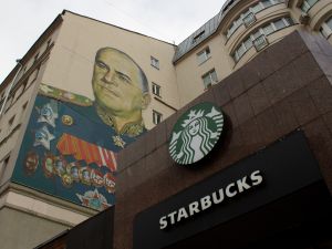 A Starbucks sign is seen alongside the mural of Georgy Zhukov, a Soviet genera