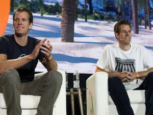 Tyler and Cameron Winklevoss sit next to eachother on stage.