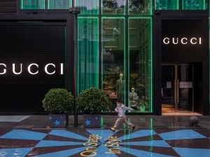 Young boy runs on the street outside a Gucci store.