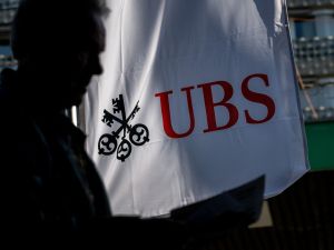 A UBS logo on a flag behind the shadowy silhouette of a man.
