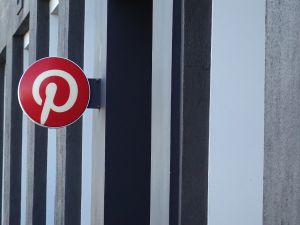A Pinterest logo hangs on a sign outside of a building.