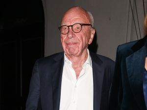 Rupert Murdoch smiles wearing a suit and glasses.