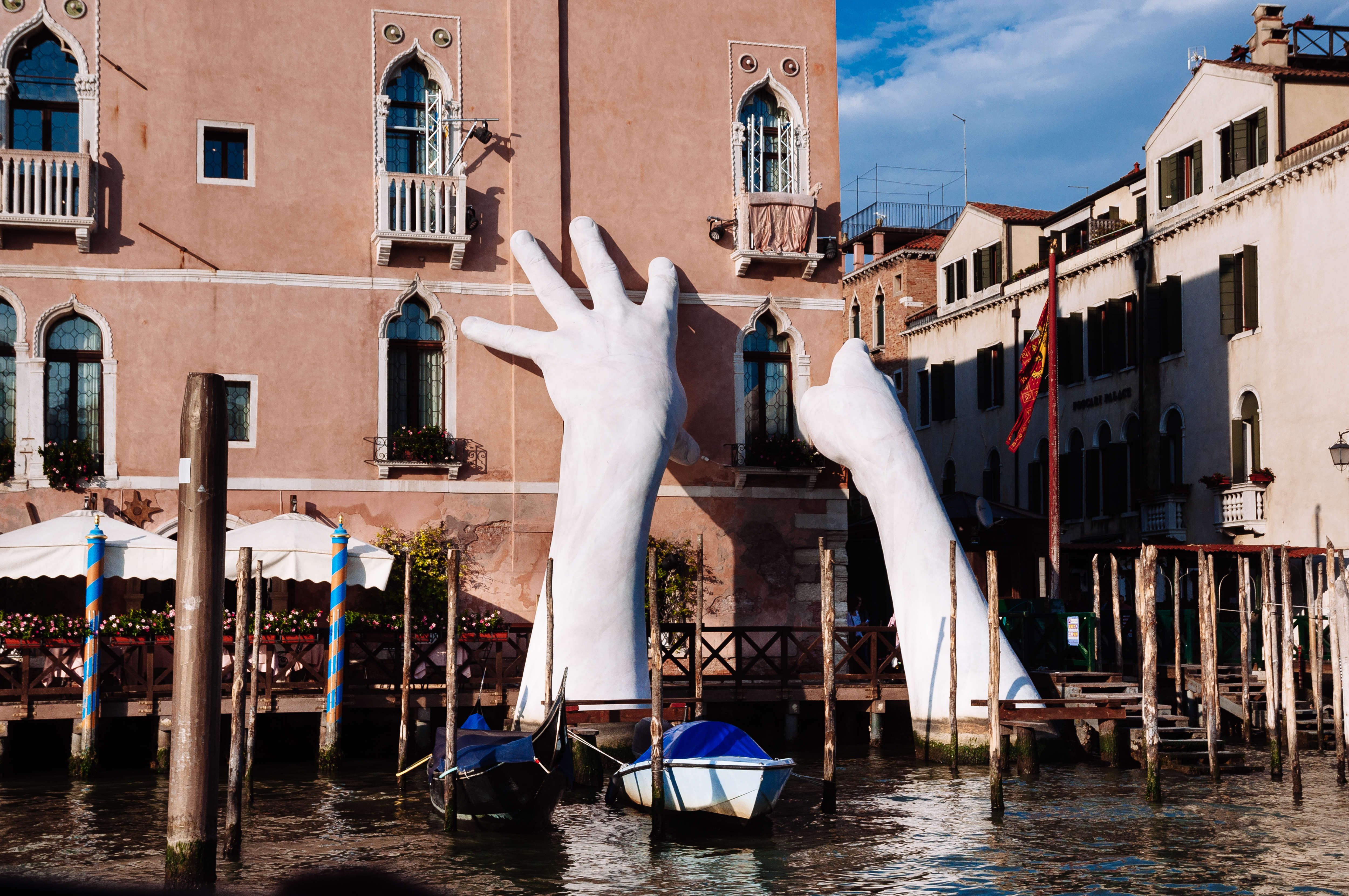 Sculpture of two large white hands rising out of canal