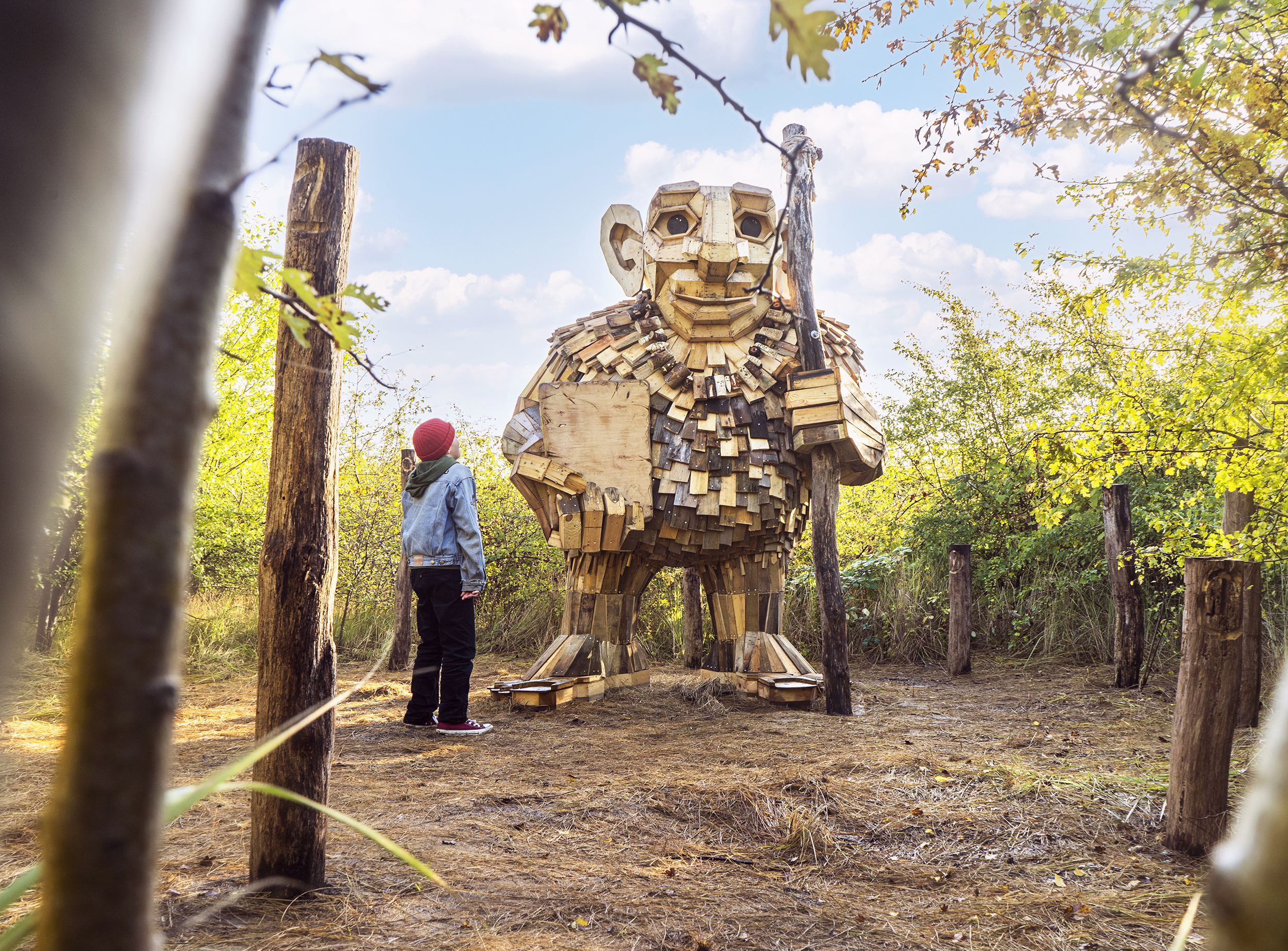 A child looks at a giant wooden troll statue