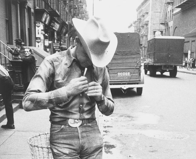 A black and white photo of a cowboy in the city