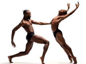 Two male dancers stand in expressive fluidity
