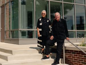 Man and woman dressed in black pose outside of building on steps