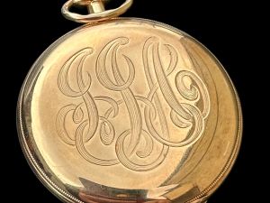 A gold circular pocket watch initialized with 'JJA'