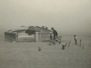 Black and white photo of man and boy running across open field to small cabin.
