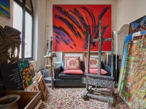 Image of art studio filled with colorful paintings, carpets and easels
