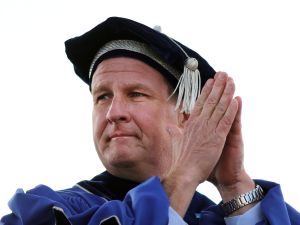 Man in graduation hat and gown puts hands together