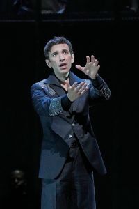 A male opera performer holds out his hands while singing