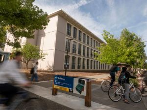 Students bike past university buildings.