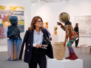 Woman observing closely a colorful sculpture by artist Yinka Shonibare at Frieze London 2023