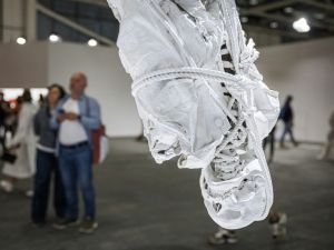 A hanging sculpture of a bound and wrapped skeleton at an art fair