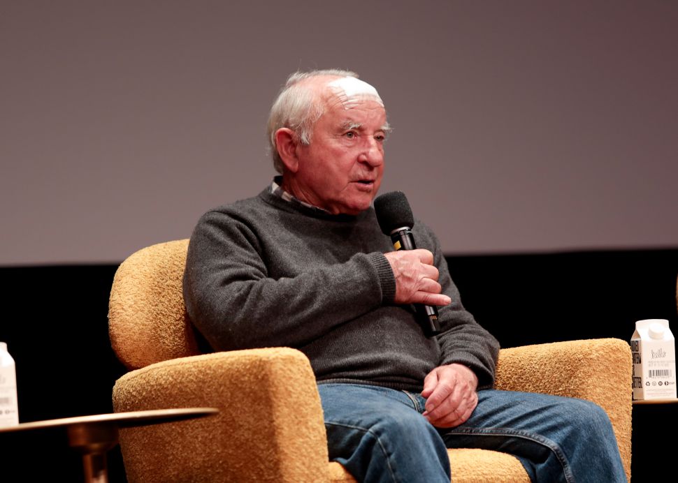 Man in sweater sits in armchair on stage