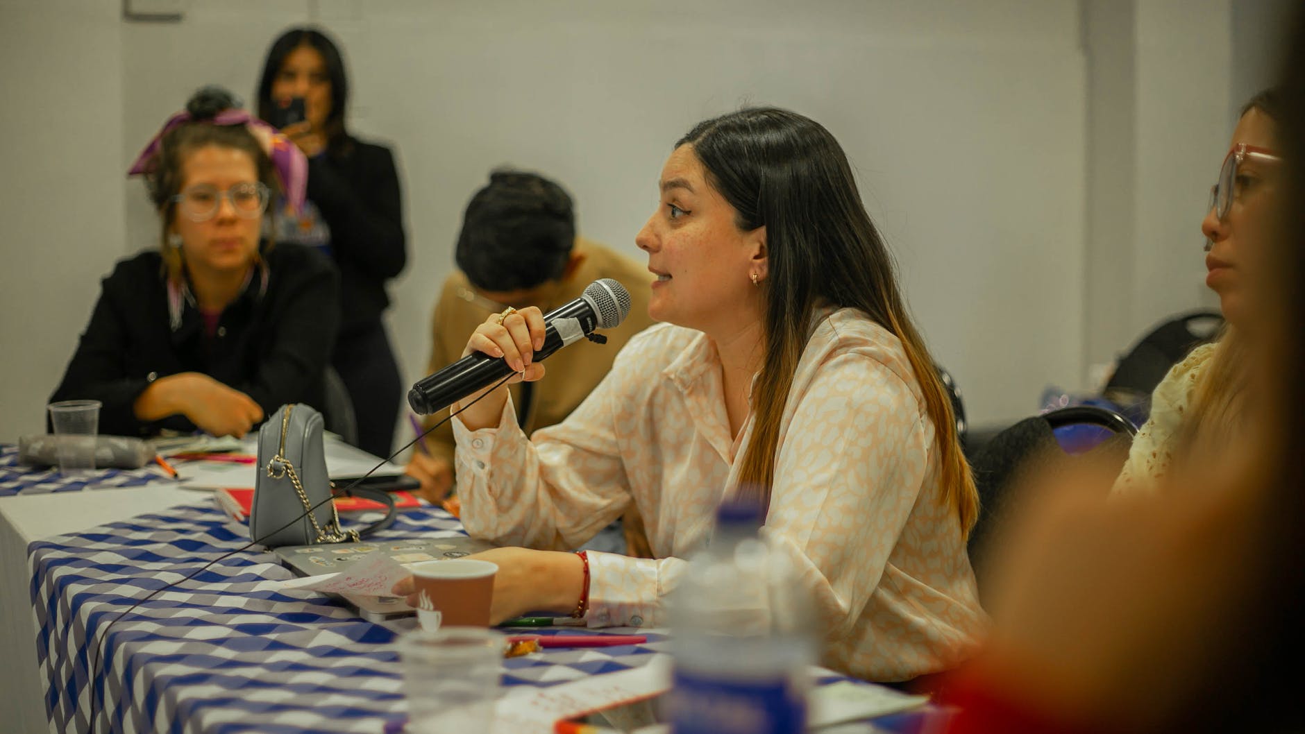 young woman sitting at a table and speaking on a microphone