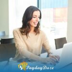 A woman sitting at a table using a laptop computer to find out the maximum payday loan amount in California