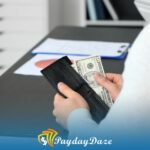 A person holding a wallet and money from installment loan in front of a desk in Connecticut