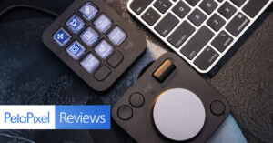 An overhead view of two Logitech devices on a desk next to a keyboard. One device has multiple customizable buttons with icons, while the other has a large dial. The image includes the PetaPixel Reviews logo in the lower-left corner.