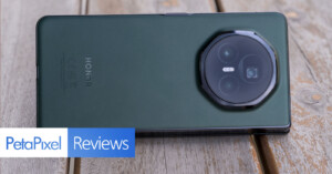 A green Honor smartphone rests on a wooden surface with its camera side facing up. A logo in the bottom left corner reads "PetaPixel Reviews.