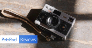 A vintage Rollei 35 AF camera with a wrist strap resting on a wooden surface, partially illuminated by sunlight. A PetaPixel Reviews logo is overlaid in the bottom left corner.