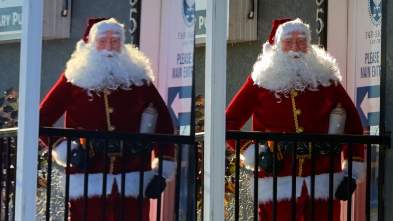 Two side-by-side images of a Santa Claus figure dressed in a red suit with white trim, black belt, and hat. The Santa has a full white beard and is standing behind a black railing. Signs and foliage are visible in the background.