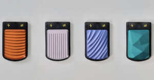 Four textured portable chargers are displayed against a light background. From left to right, they are orange with wavy ridges, gray with vertical ridges, blue with horizontal waves, and teal with a geometric pattern. Each features a lightning bolt symbol.